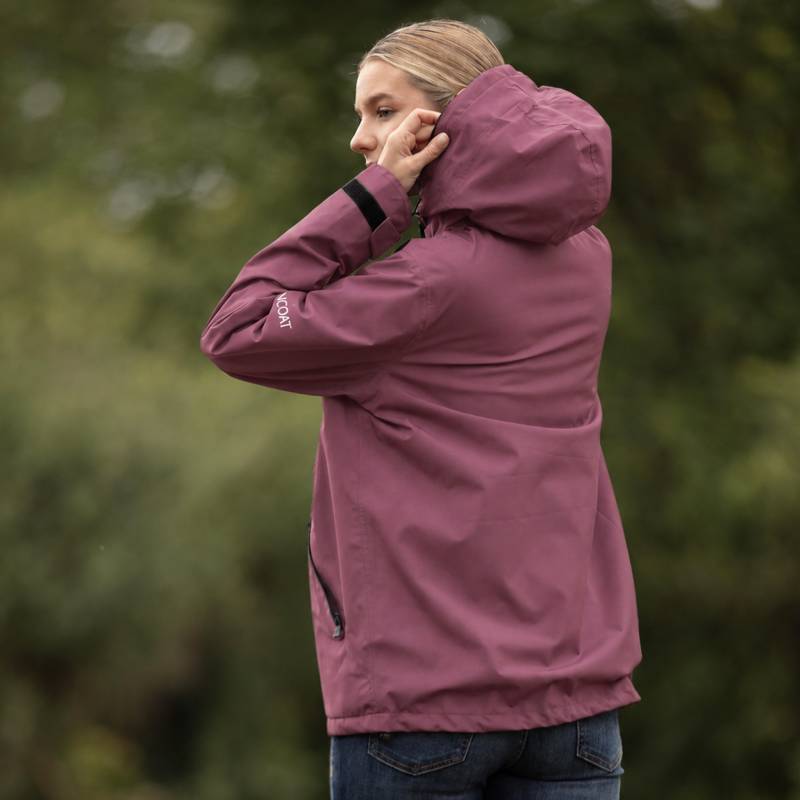 Reinwear Reincoat Smock Lite Adult Bloom, maroon, hood up, outdoors with greenery backdrop.