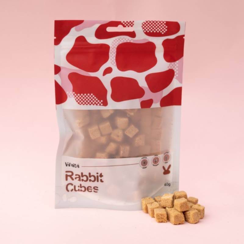 Waita Freeze Dried Rabbit Cubes Dog &amp; Cat 40g bag with cubes in front, on a pink background.