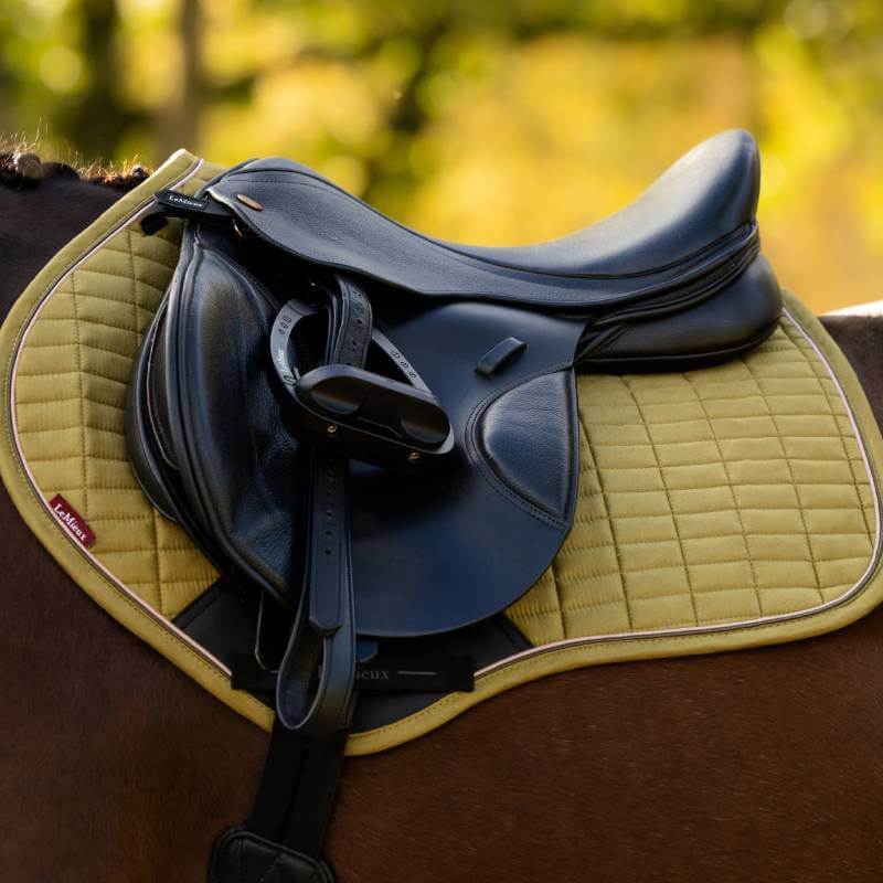 LeMieux Suede Close Contact Square Gooseberry on a horse, blurred greenery in the background.