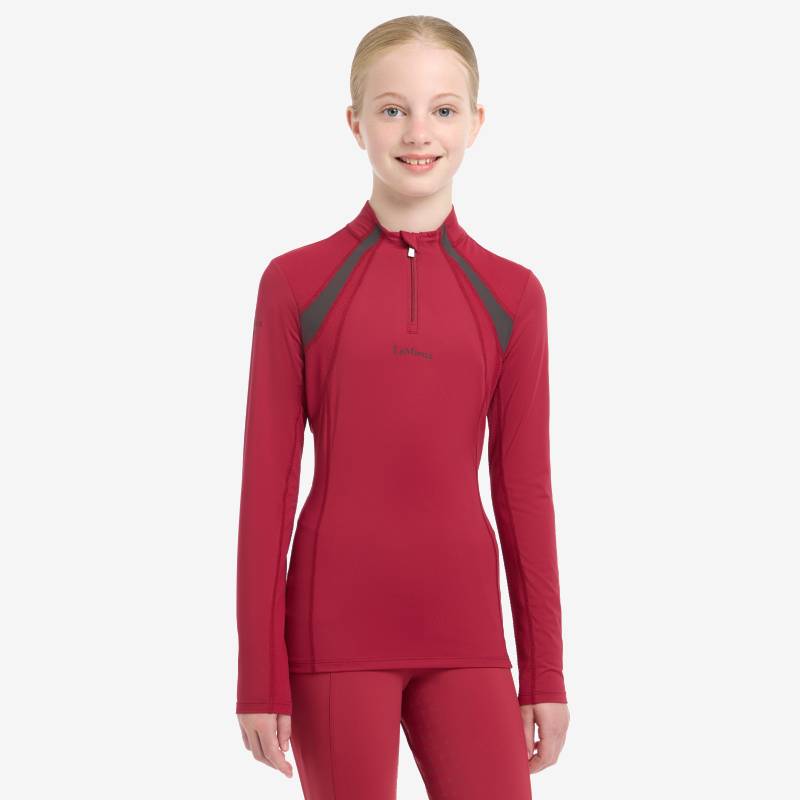 Smiling young girl in a LeMieux Mia Mesh Baselayer Ember by LeMieux, looking at the camera.
