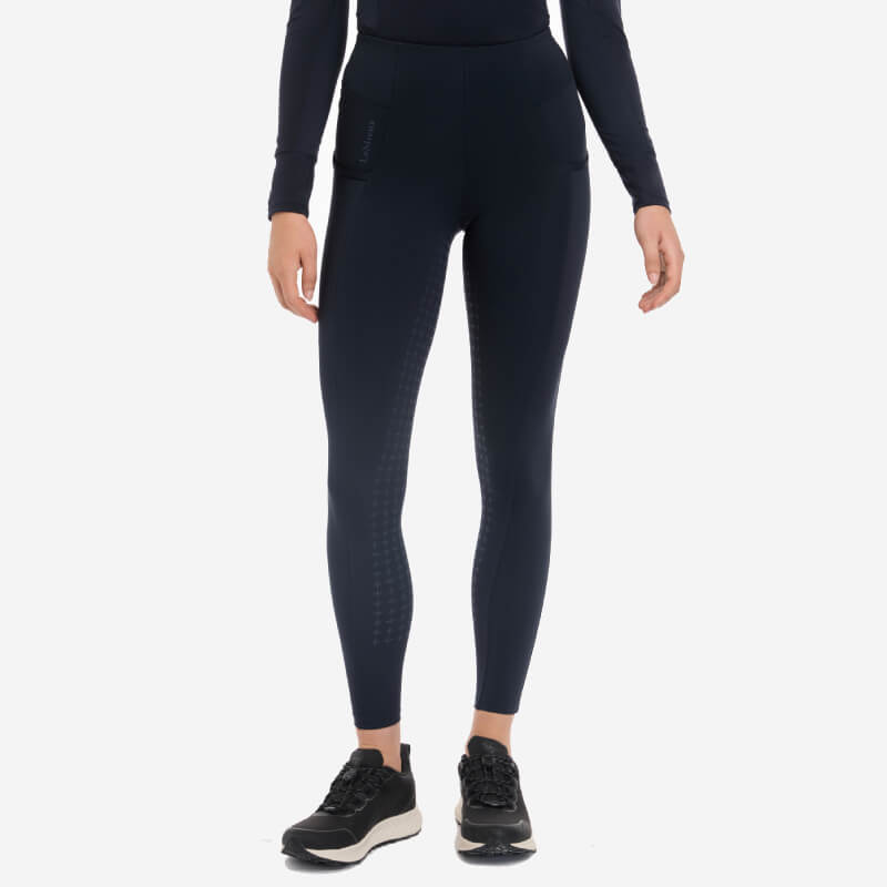 Person wearing LeMieux Naomi Pull On Breech Navy Full Seat and black sneakers, white background.
