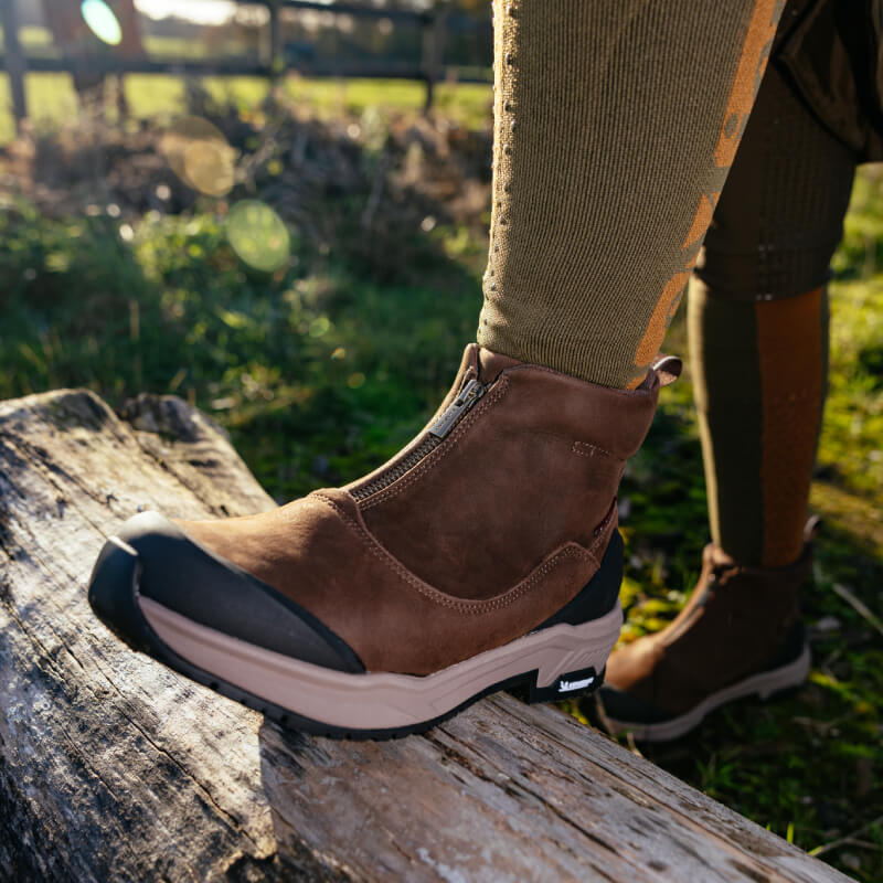 Close-up of LeMieux Trex Waterproof Zip Boots Brown worn outdoors with tan leggings.