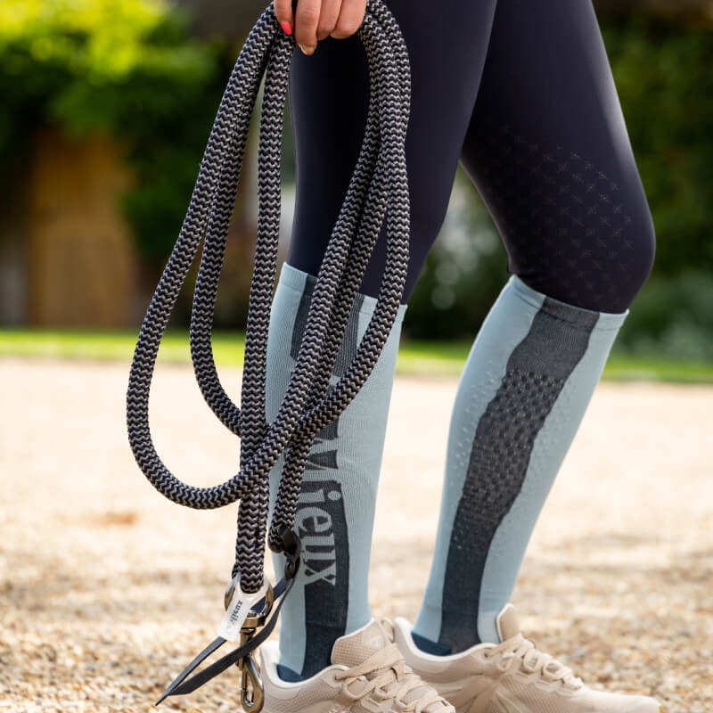 Person holding a LeMieux Training Leadrope Navy/Grey, wearing light blue leggings and beige sneakers.