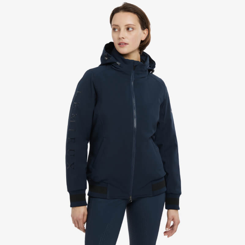 Woman in LeMieux Ladies Team Jacket Navy with hood, looking to the side.