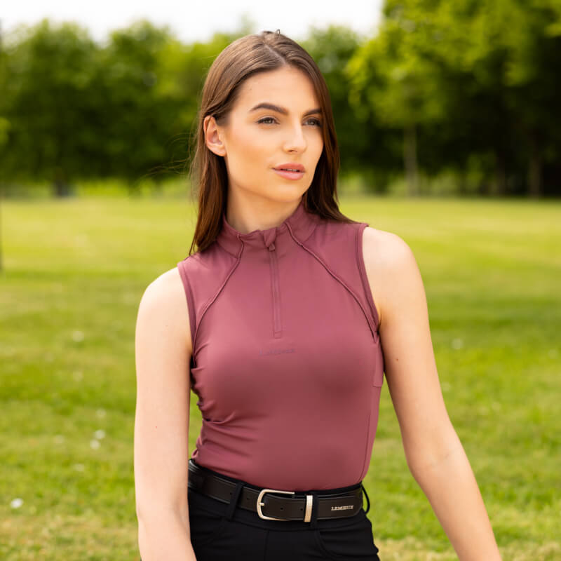 Woman in LeMieux Maria Mesh Sleeveless Baselayer Rosewood on a grassy field.