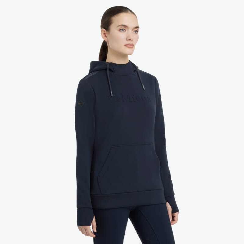 Woman wearing LeMieux Classique Hoodie Navy and pants, standing against a white background.