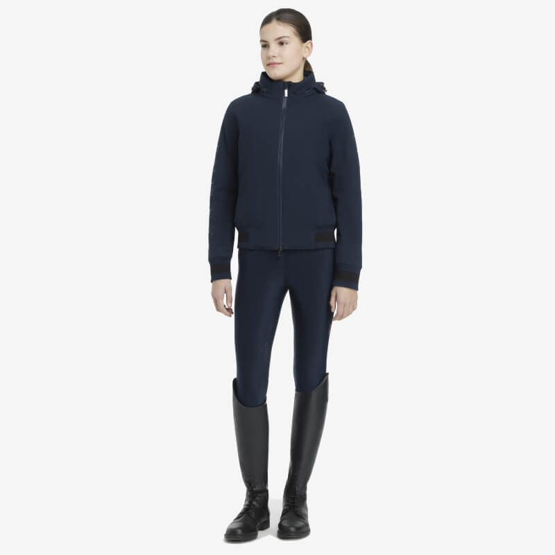 Person wearing a LeMieux Young Rider Team Jacket Navy, navy pants, and black knee-high boots.