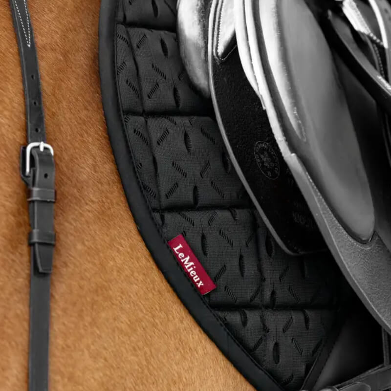 Close-up of a black saddle on a brown horse with the LeMieux 3D Mesh Self-Cool Eurojump Square.