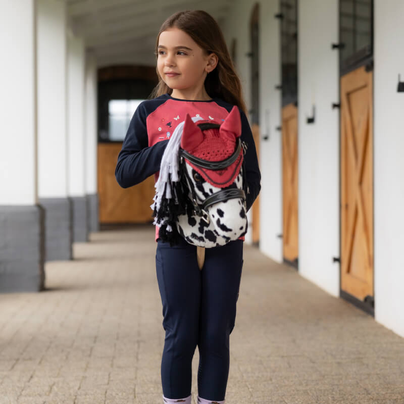 Young girl with a LeMieux Hobby Horse Dakota in a stable corridor.