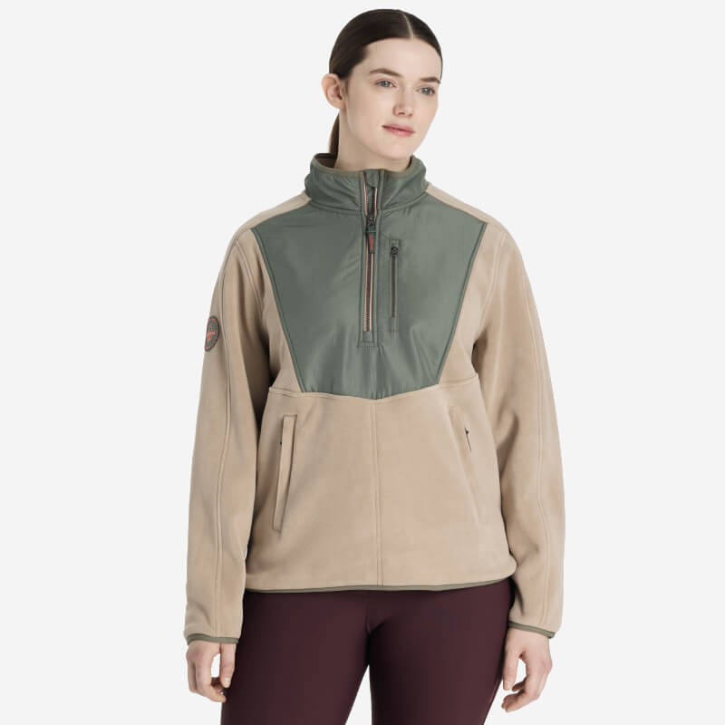 Woman in the LeMieux Clara Hybrid Fleece Rosemary, a stylish transitional jacket by LeMieux.