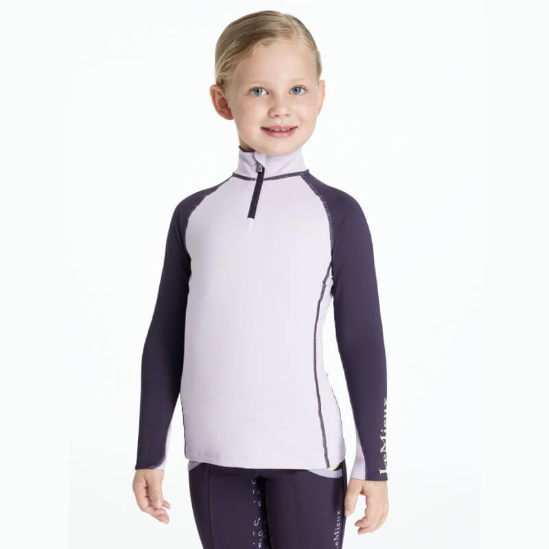 Smiling girl in LeMieux Mini Baselayer Lilac athletic top with UV50+ protection.