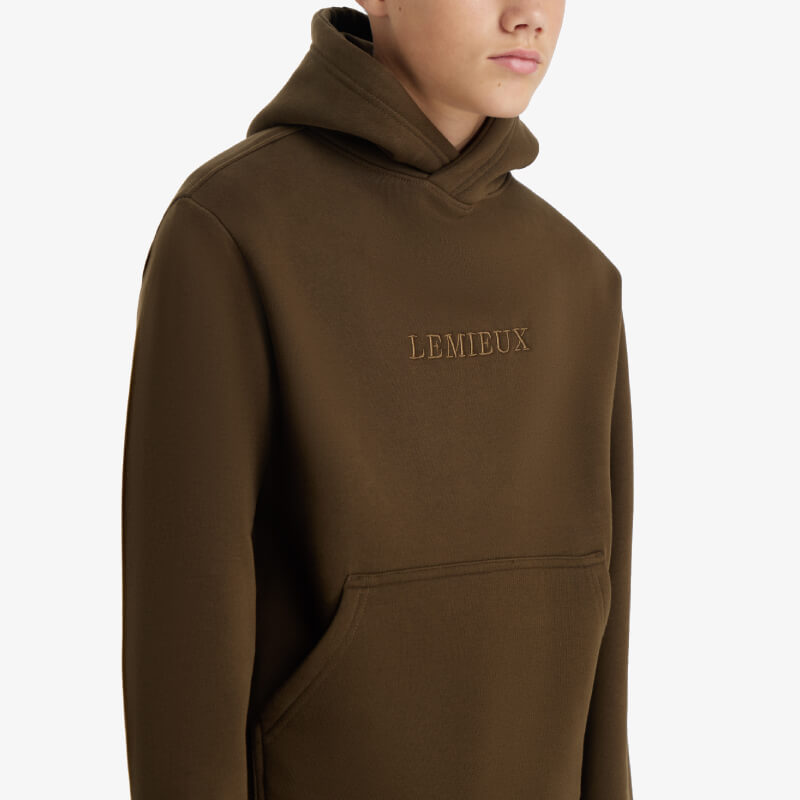 Boy in a brown LeMieux Young Rider Boys Hoodie Alpine with LEMIEUX on the front.
