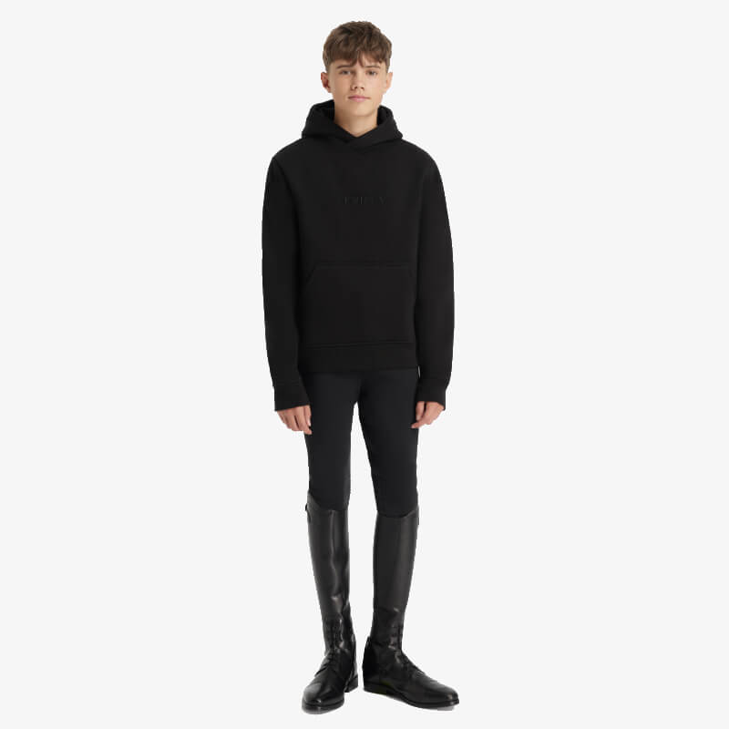 Young rider in LeMieux Young Rider Boys Hoodie Black, black pants, and tall black boots.