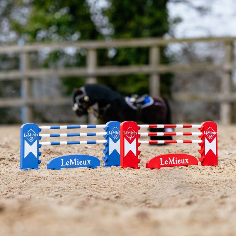 LeMieux Toy Pony Jump Set Benetton/Chilli/White on sand with blurred pony and fence behind.