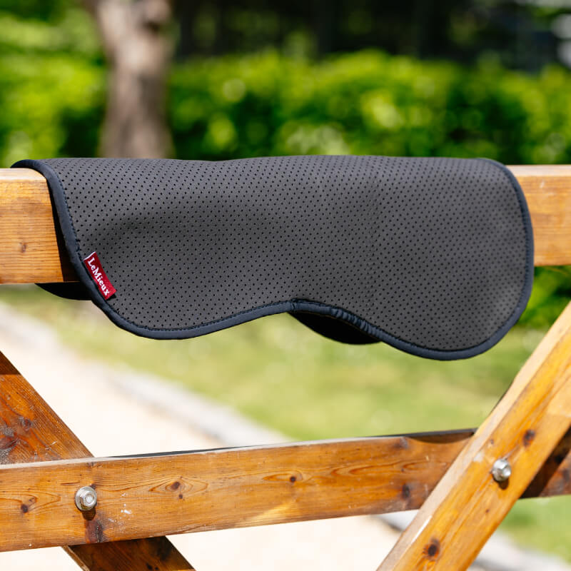 LeMieux Non-Slip Half Pad Black by LeMieux draped over a wooden fence outdoors.