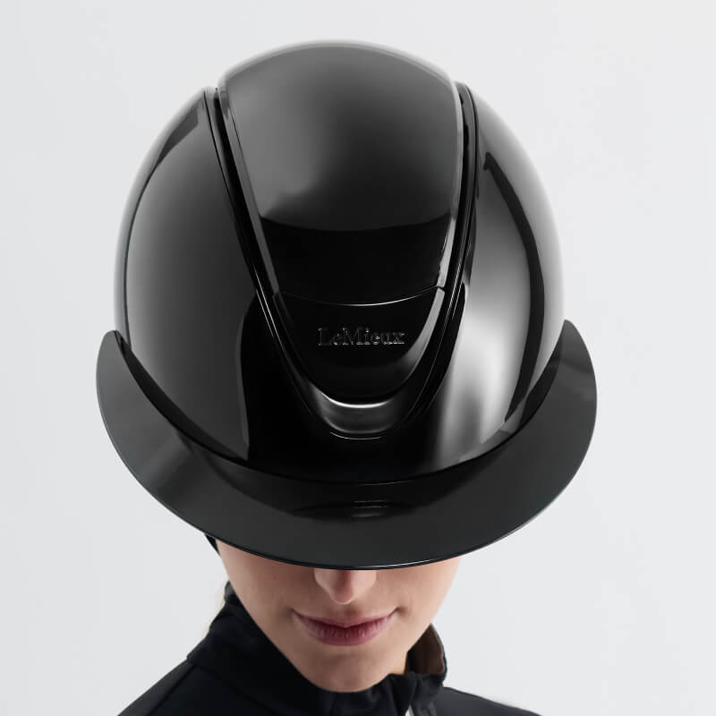 Woman wears LeMieux Verv® Magnetic Top Panel Gloss Black for a sleek, stylish riding look.