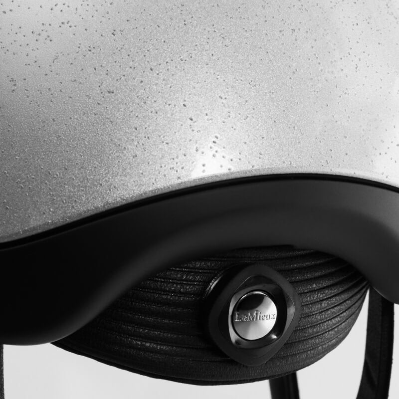 Close-up of the LeMieux Vexa® Skull Helmet Silver with water droplets and a LeMieux logo.