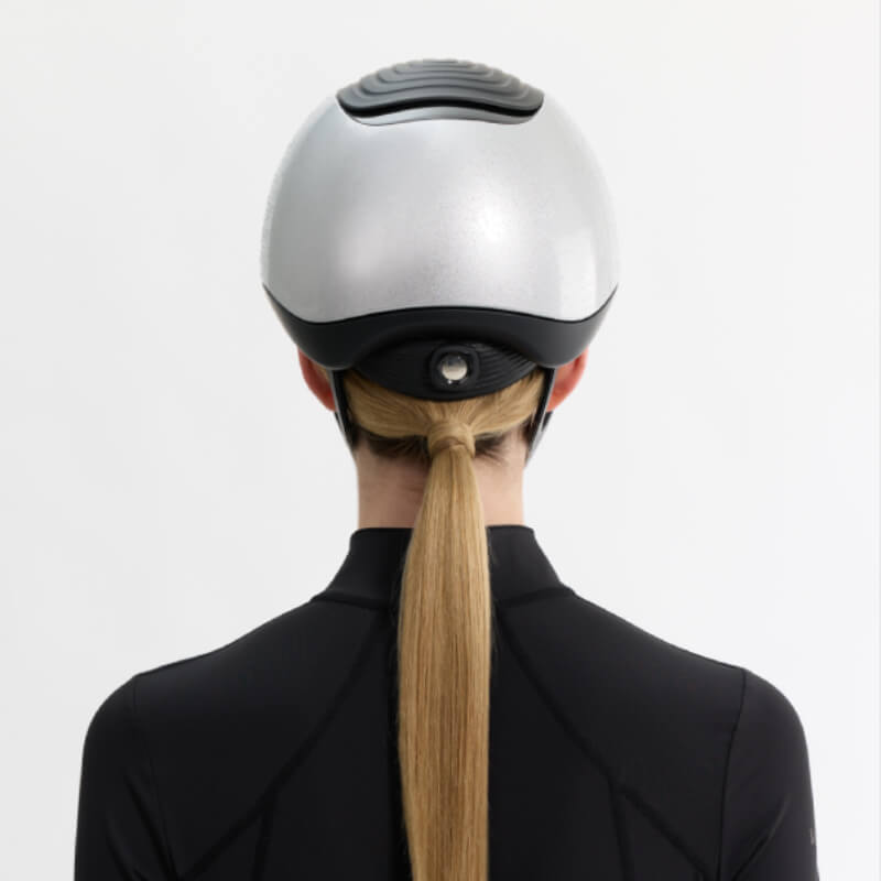 Person with long blonde ponytail wears LeMieux Vexa® Skull Helmet Silver, seen from behind.