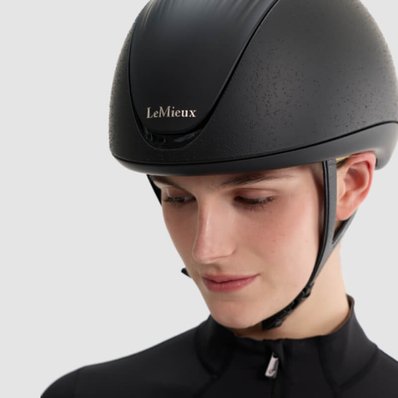 Person wearing a LeMieux Vexa® Skull Helmet Black, looking down against a light background.