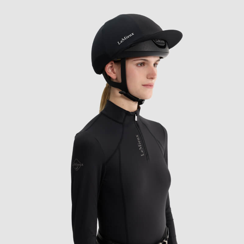 Woman wearing LeMieux Vexa® Skull Helmet Black, posing against a light gray background.