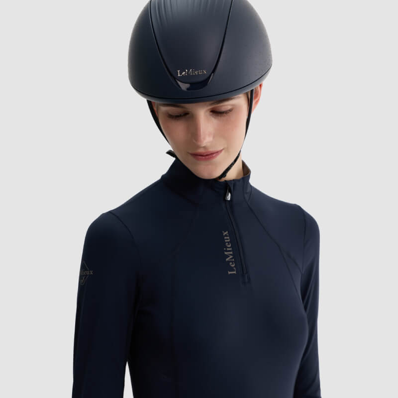 Woman wearing a LeMieux Vexa® Skull Helmet Navy, looking down against a plain background.