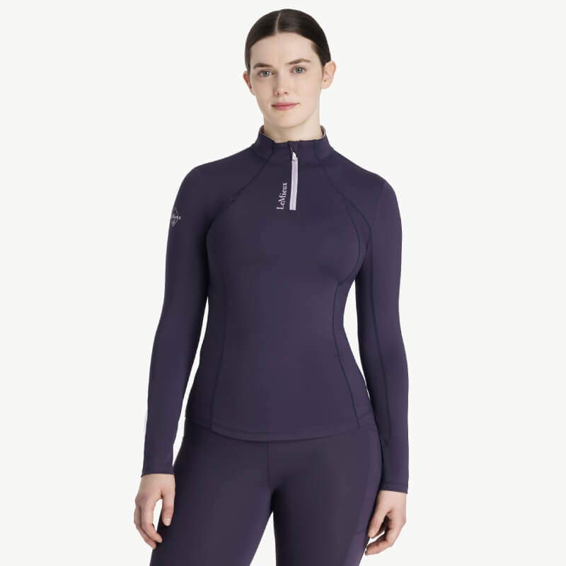 Woman in a fitted LeMieux Classique Baselayer Juniper, standing facing forward.