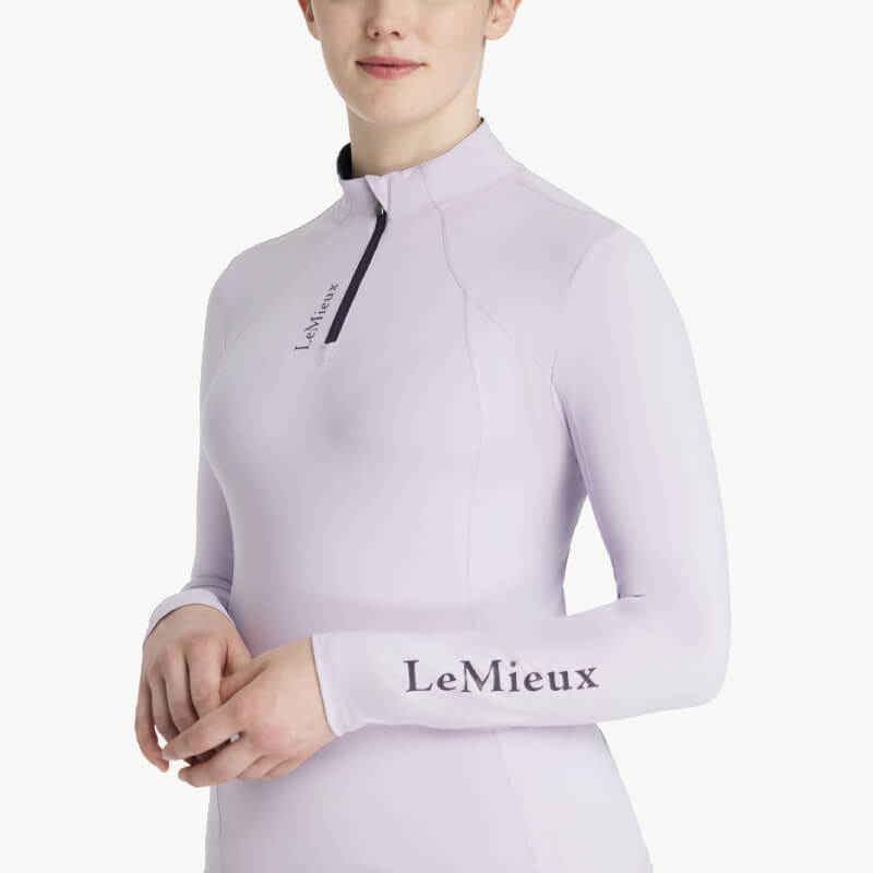 Woman in a LeMieux Classique Baselayer Lilac with zipper, standing against a white background.
