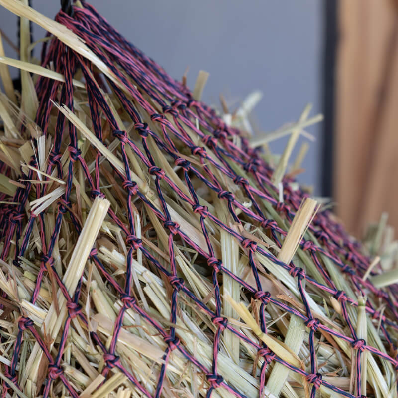 Close-up of hay in a LeMieux Hippo Lite Haynet Navy/Mallow for horse feeding.