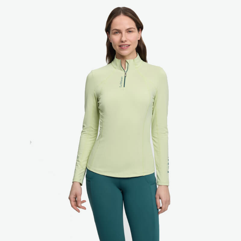 Woman in a LeMieux Classique Baselayer Macaron and teal pants smiles at the camera.