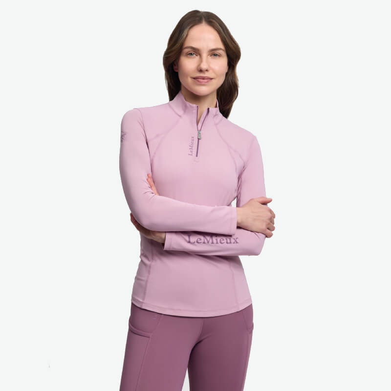 Woman smiles confidently in a LeMieux Classique Baselayer Fondant, arms crossed.