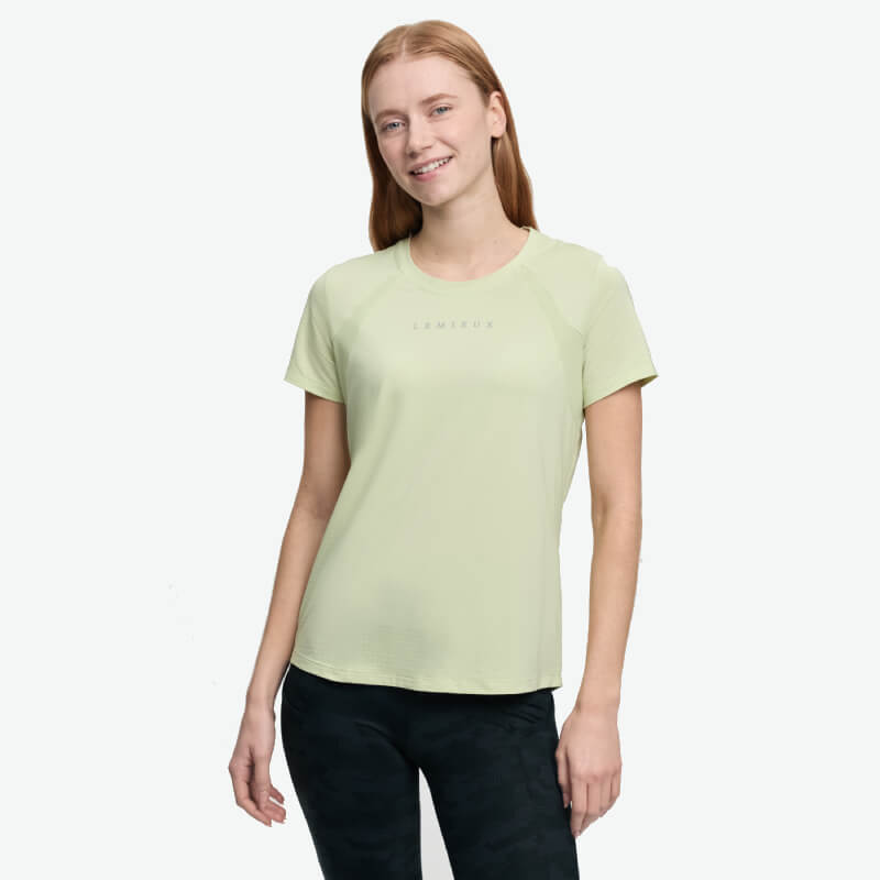 Woman in a LeMieux Sports T-Shirt Macaron and black pants smiling against a white background.