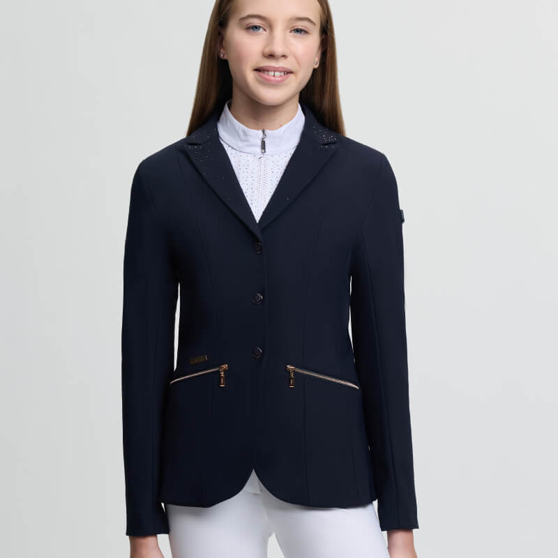 Teen girl in a LeMieux Brilliance Junior Pro Show Jacket Navy smiles against a plain background.