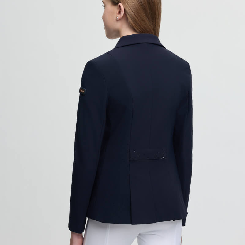 Young rider in a LeMieux Brilliance Junior Pro Show Jacket Navy and white pants, seen from behind.