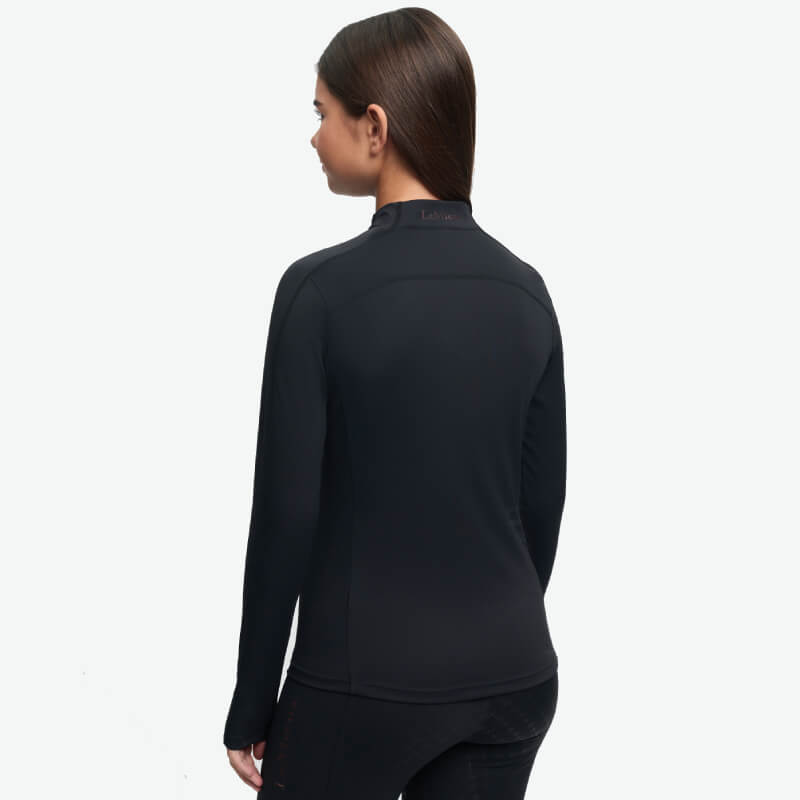 Woman with straight brown hair in a black LeMieux Young Rider Sparkle Baselayer, shown from behind.