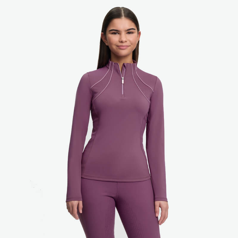 Girl in LeMieux Young Rider Airflow Baselayer Mallow smiles, facing forward, on white background.