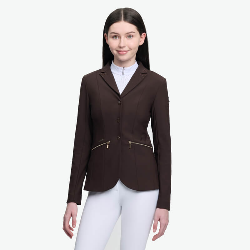 Young rider wears the LeMieux Brilliance Junior Pro Show Jacket Espresso and white pants.