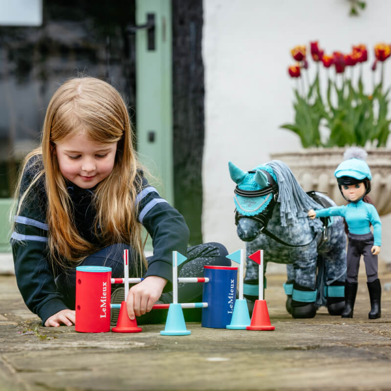 Young girl enjoys creative play with the LeMieux Toy Pony Course Builder Set Multi.