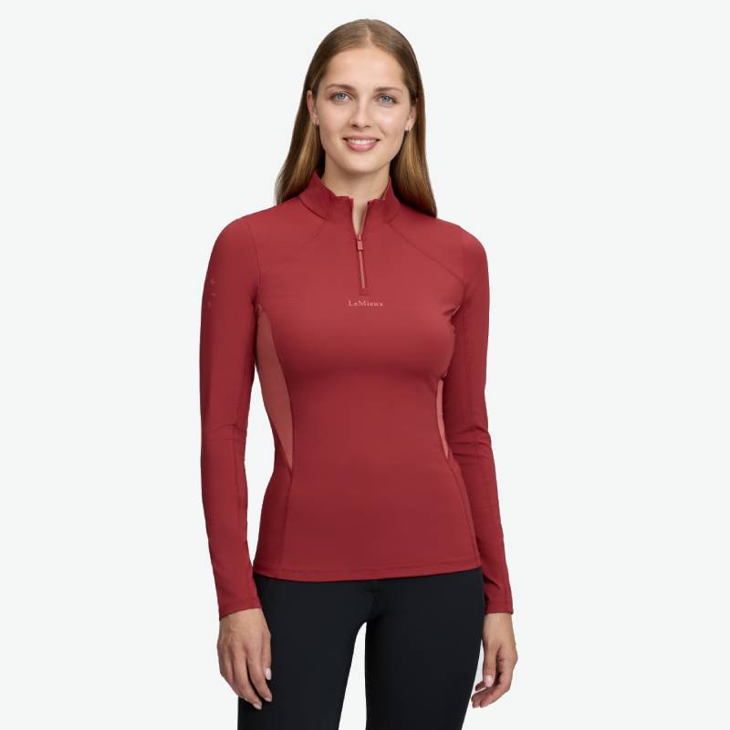 Woman in a LeMieux Classique Baselayer Russet and black pants, standing and smiling.