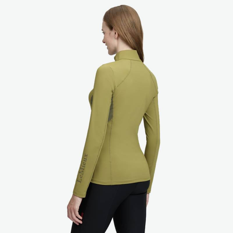 Woman in a gooseberry LeMieux Classique Baselayer and black pants, facing away from camera.