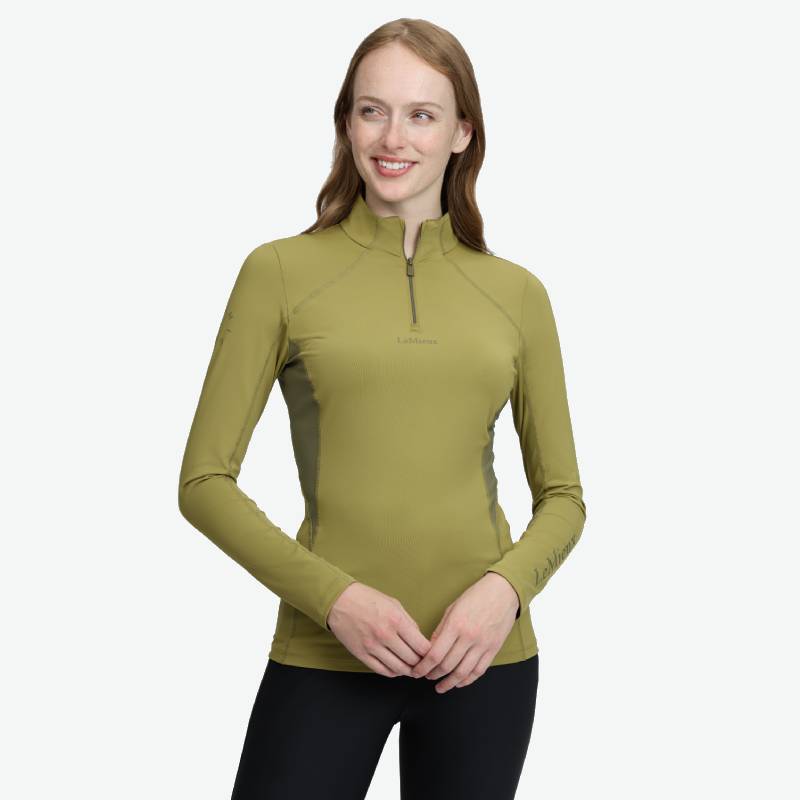 Woman in a LeMieux Classique Baselayer Gooseberry and black pants, smiling, looking aside.