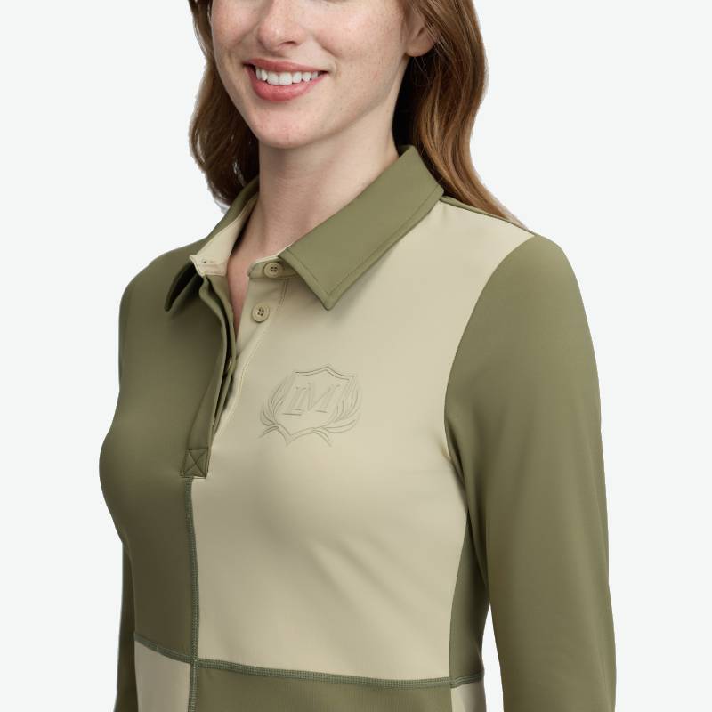 Woman smiling in a LeMieux Harlequin Rugby Shirt Baselayer Willow/Pear with crest on chest.