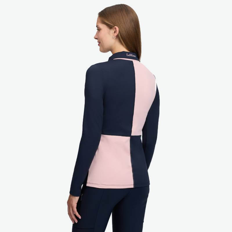 Woman in LeMieux Harlequin Rugby Shirt Baselayer Petal/Navy, back view, logo on collar.