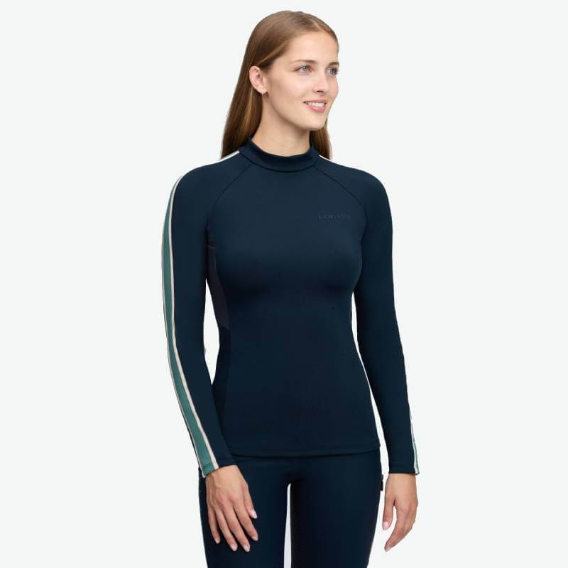 Smiling woman in LeMieux Talia Turtle Neck Baselayer Navy with chic striped sleeves.
