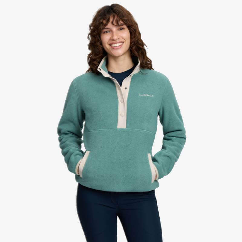 Person in LeMieux Piper Popper Fleece Aloe, hands in pockets, smiling at the camera.