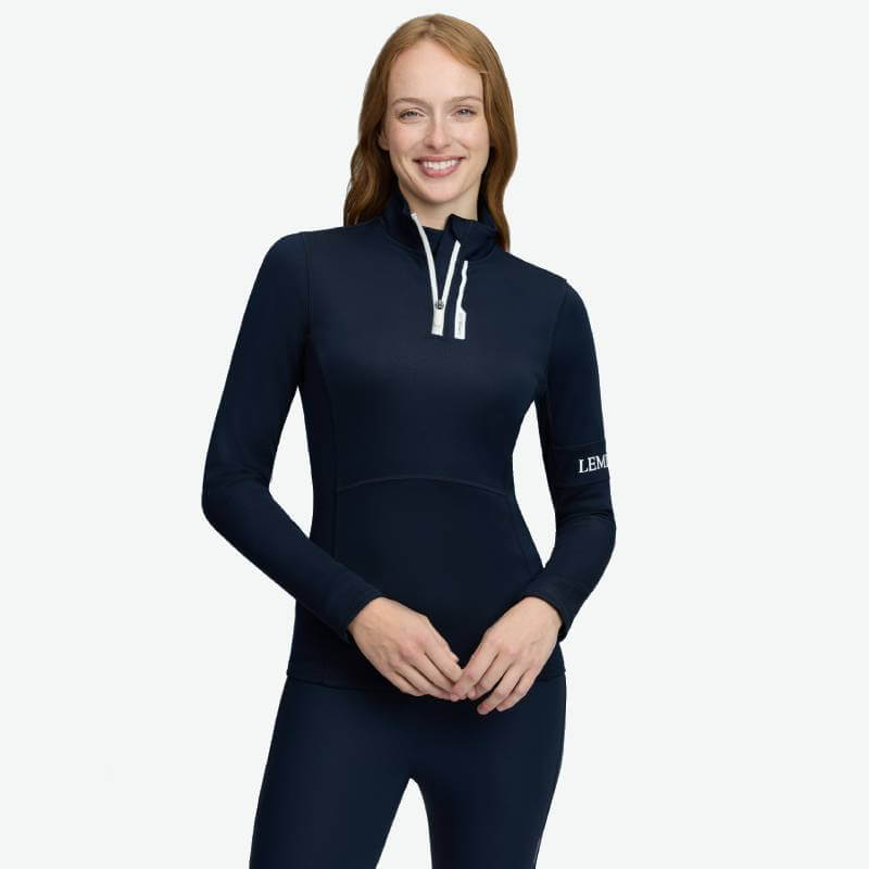 Woman smiles in LeMieux Matila Midlayer Navy, a lightweight insulating top by LeMieux.