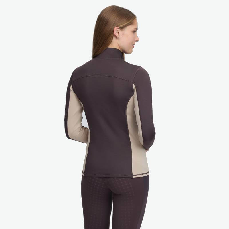 Woman in LeMieux Matila Midlayer Cocoa, crafted from technical fabric with beige panels.