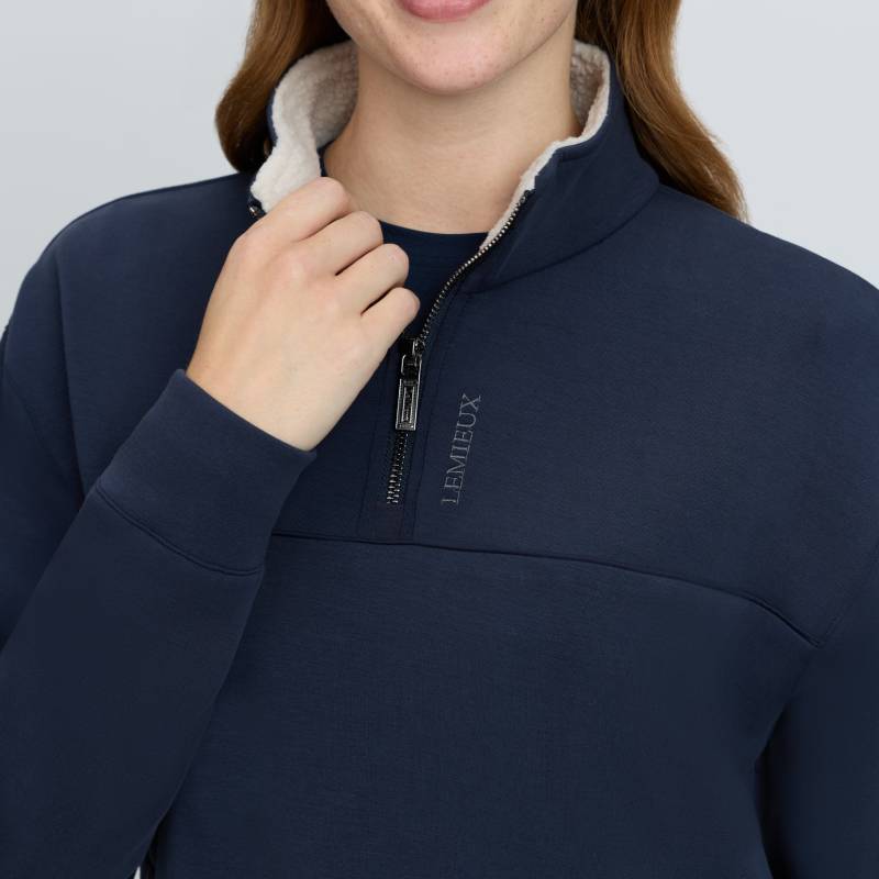 Woman in a LeMieux Scarlet Quarter Zip Sweat Navy with white fleece lining, touching her collar.