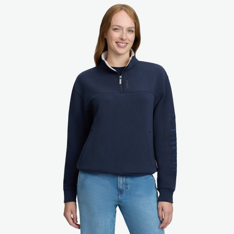 Woman in a LeMieux Scarlet Quarter Zip Sweat Navy and jeans, smiling against a white background.