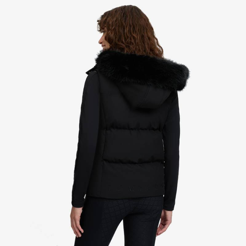 Woman wearing LeMieux Margot Hooded Gilet Black with fur-trimmed hood, viewed from the back.