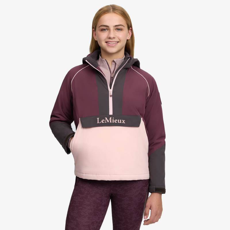 Smiling young woman in LeMieux Bailey Waterproof Anorak Bramble, against a plain background.
